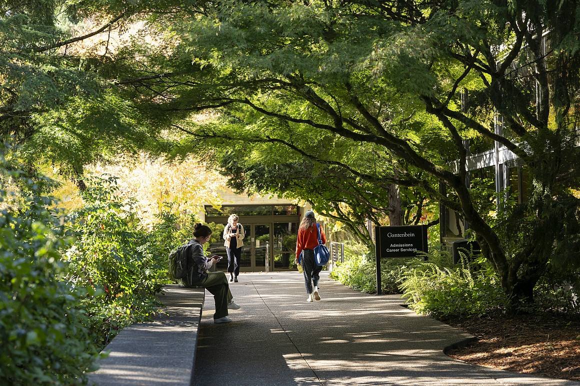 Exterior of the law campus on a sunny day, with students walking on a path.
