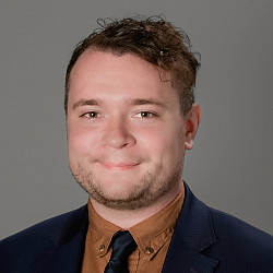 Headshot of Matt, smiling at the camera, wearing a suit and tie.