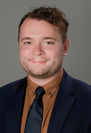 Headshot of Matt, smiling at the camera, wearing a suit and tie.