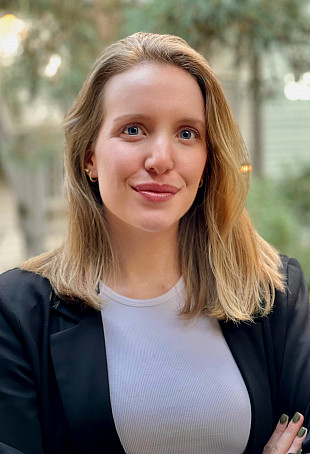 Carter Jane smiling at the camera wearing a white top and a black blazer.