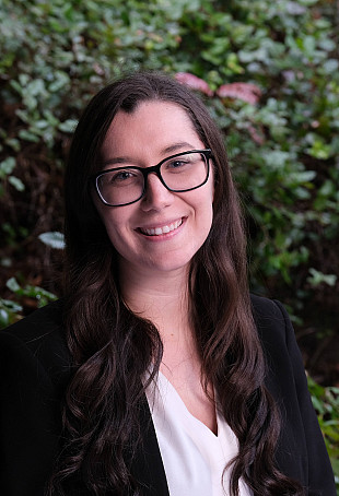 Rachel smiling outside wearing glasses.