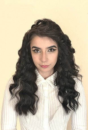 Daniella looking at the camera and wearing a white top.