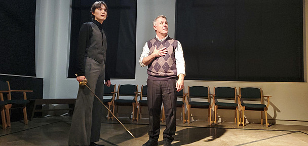 Two male presenting actors look into the distance.