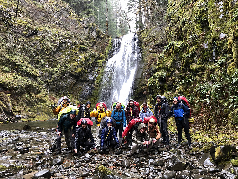 Participants pose in front of a waterfall on a training trip.