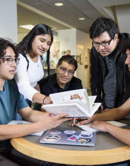 Professor Freddy Vilches at a round table with 4 other students looking over study materials.
