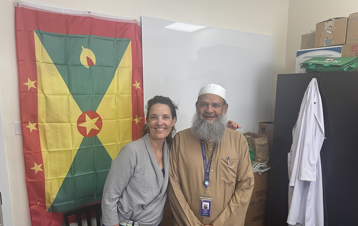 Dr. Emily Talkington with Dr. Bhaiyat in front of Grenadian flag.
