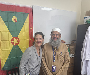Dr. Emily Talkington with Dr. Bhaiyat in front of Grenadian flag.