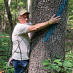 Professor Tom Buchele hugging one of the trees he's trying to save in an ongoing Earthrise lawsuit (plus Tom's dog Sam).