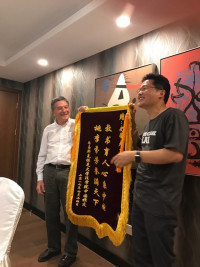 Jun Ge ?95 presents a ceremonial scroll to Dean Emeritus Steve Kanter.