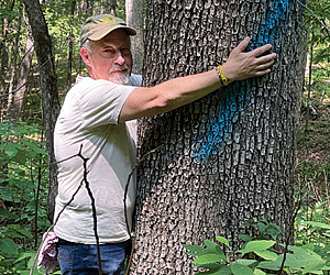 Professor Tom Buchele hugging one of the trees he's trying to save in an ongoing Earthrise lawsuit (plus Tom's dog Sam).