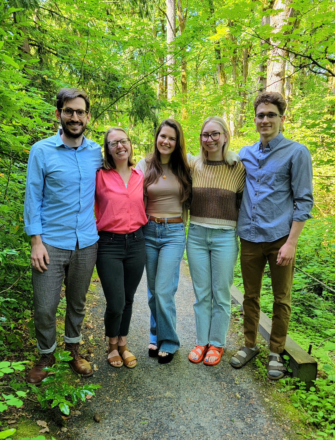 Five summer clerks standing on a forested path.
