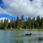 A lake with trees around it and people canoeing in the water.