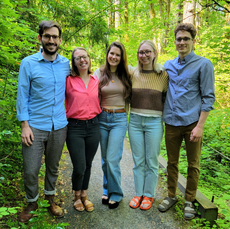 Five summer clerks standing on a forested path.