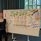 Artist Molly Chidsey stands beside Fall in Love with the Future, a live visual illustration capturing participants' collective visions fo...