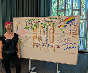 Artist Molly Chidsey stands beside Fall in Love with the Future, a live visual illustration capturing participants' collective visions fo...