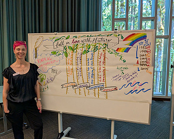 Artist Molly Chidsey stands beside Fall in Love with the Future, a live visual illustration capturing participants' collective visions fo...