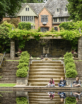 Students sitting by the reflecting pool with the Manor House in the background.