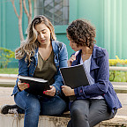 Two people sit together and look at a notebook.