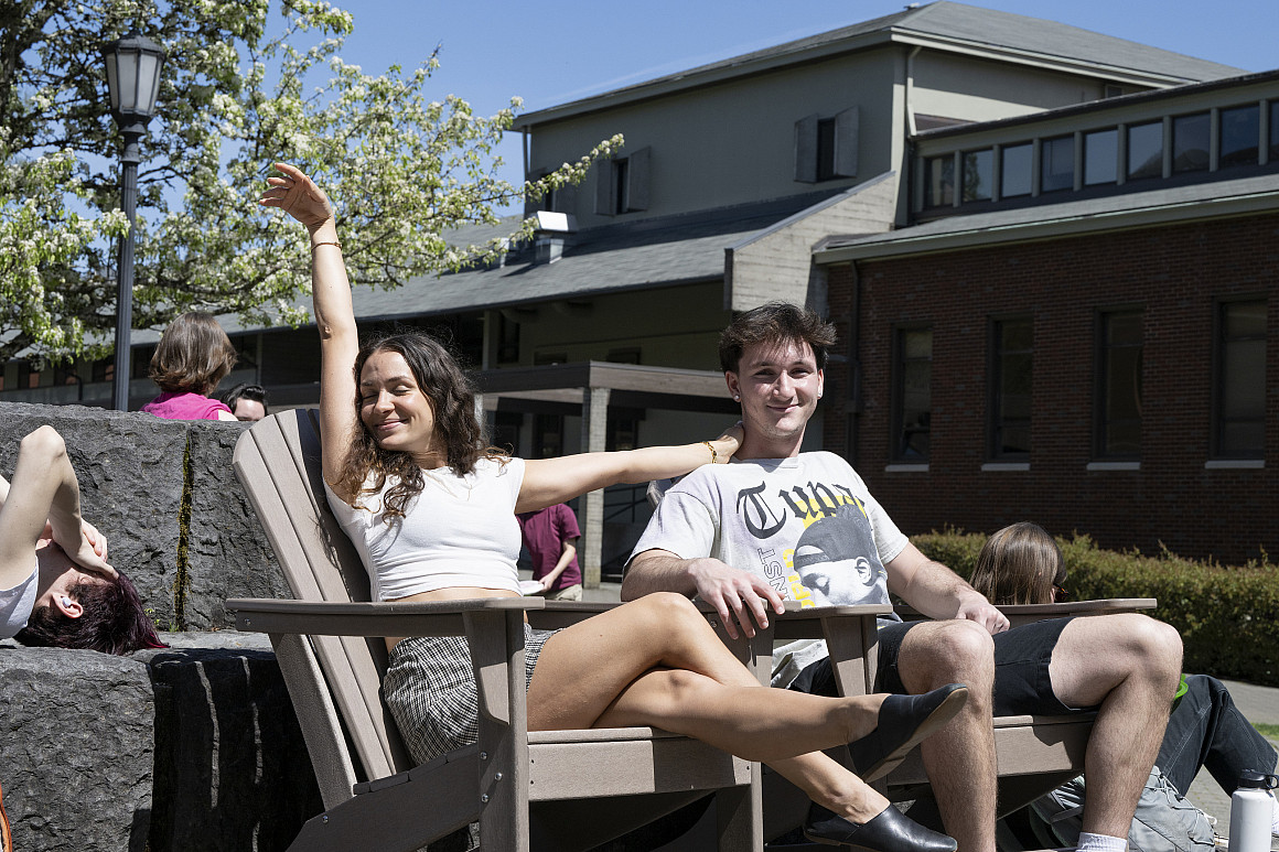 Students lounging outside in the sun on campus.